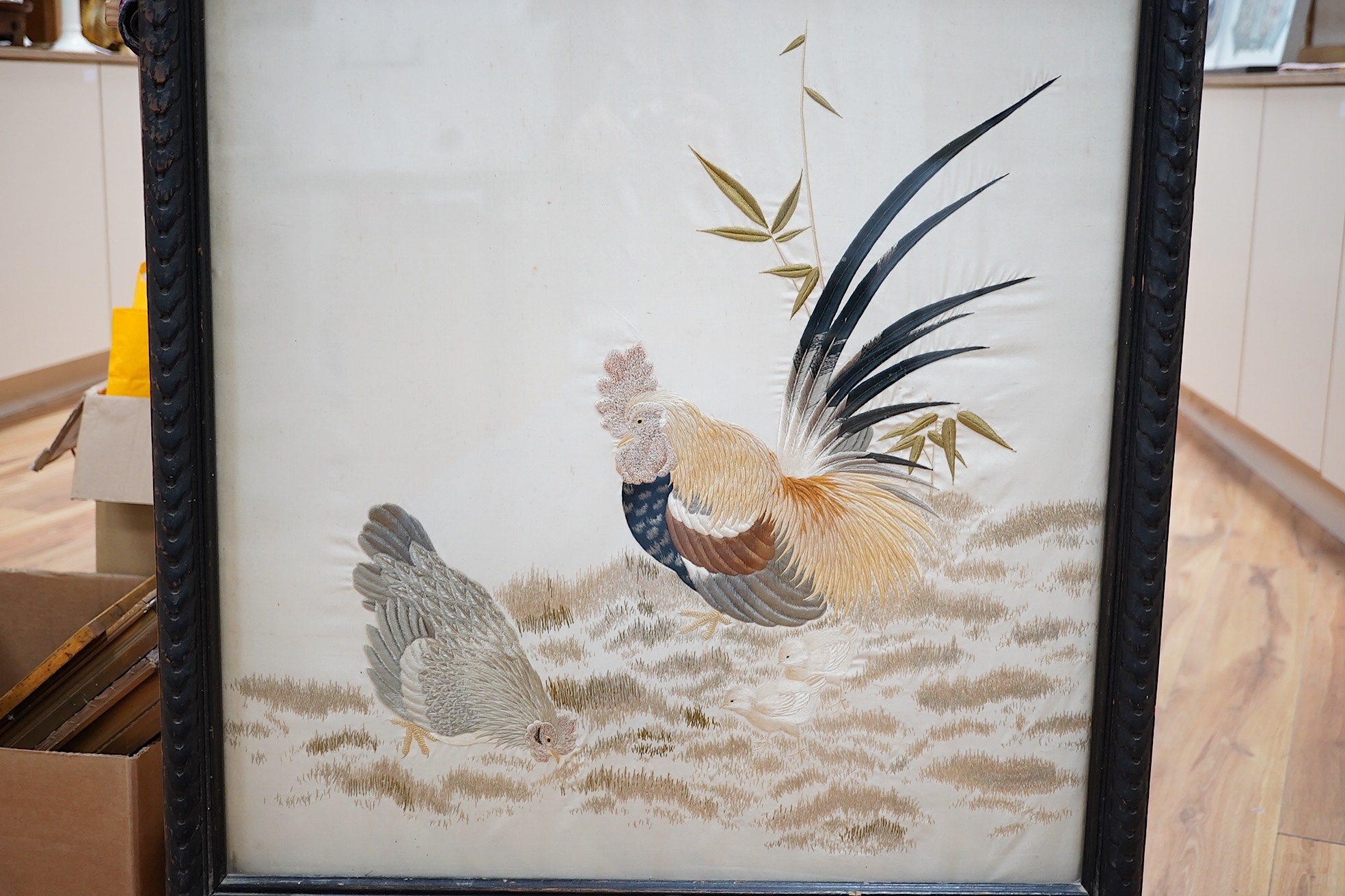 A Victorian fire screen inset with a Japanese cream silk embroidered panel of a cockerel, hen and two chicks, beautifully embroidered with rows of couched silk on the bodies of all the birds, their feathers and faces inc